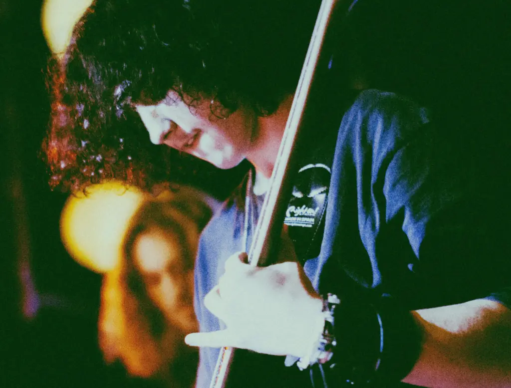 Music student playing guitar in a live show. Shot on film with studio lighting. Student concentrating intensely.