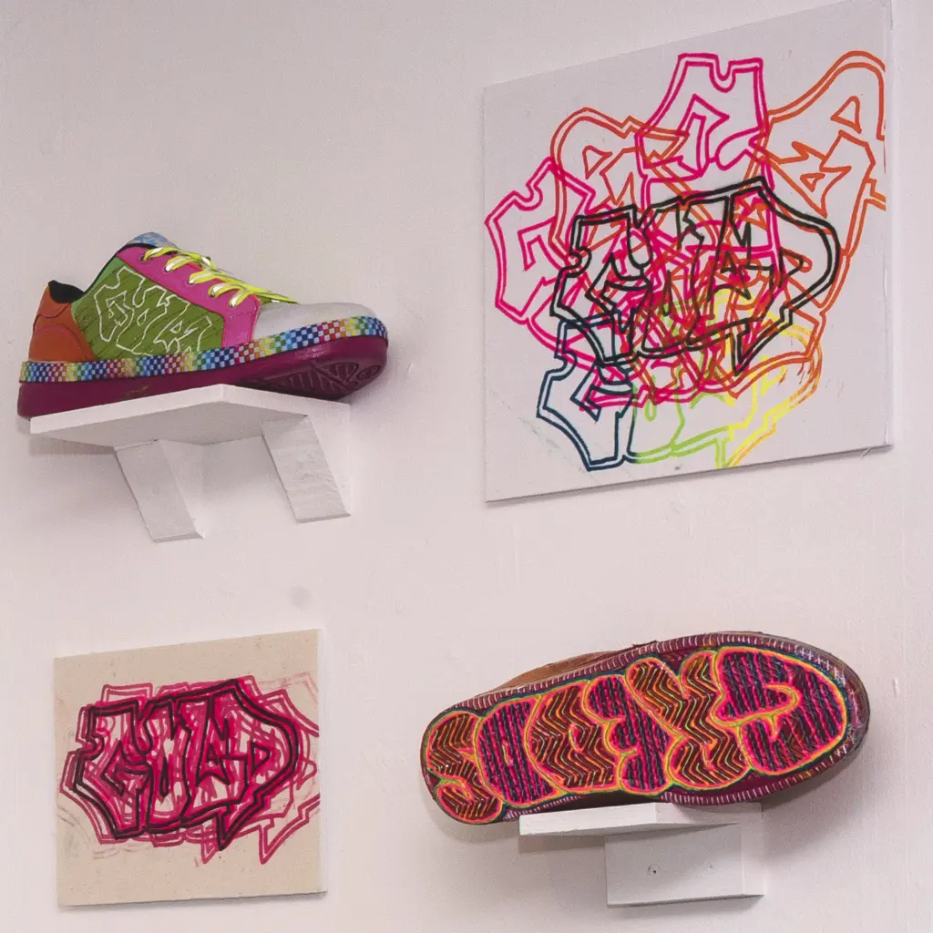 An art piece produced by a HCA Art, Design and Communication student comprising of brightly decorated trainers and graffiti art.