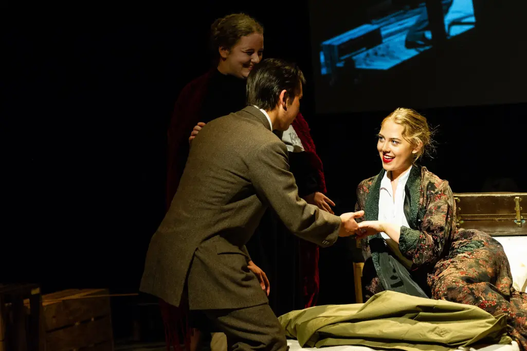 A trio of HCA performing arts students mid performance, the three actors lit under a spotlight at a pivotal moment.