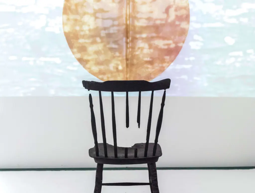 A broken chair with a projected image in front of it