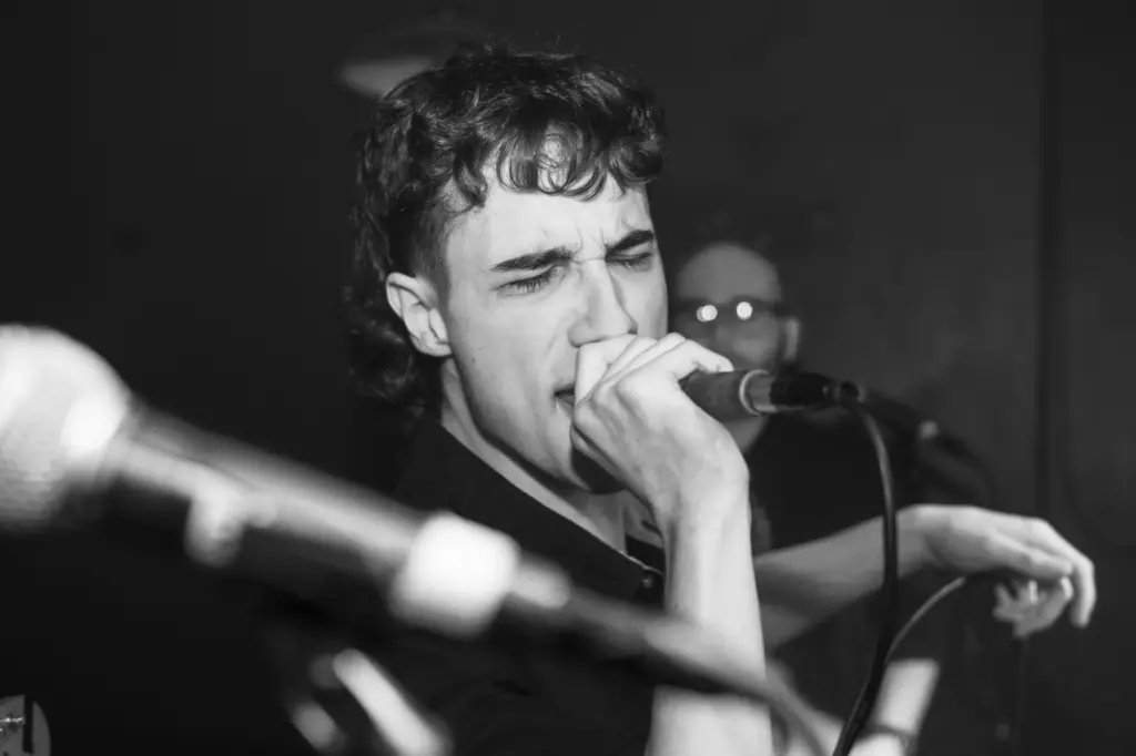 A black and white photo of a man singing into a microphone.