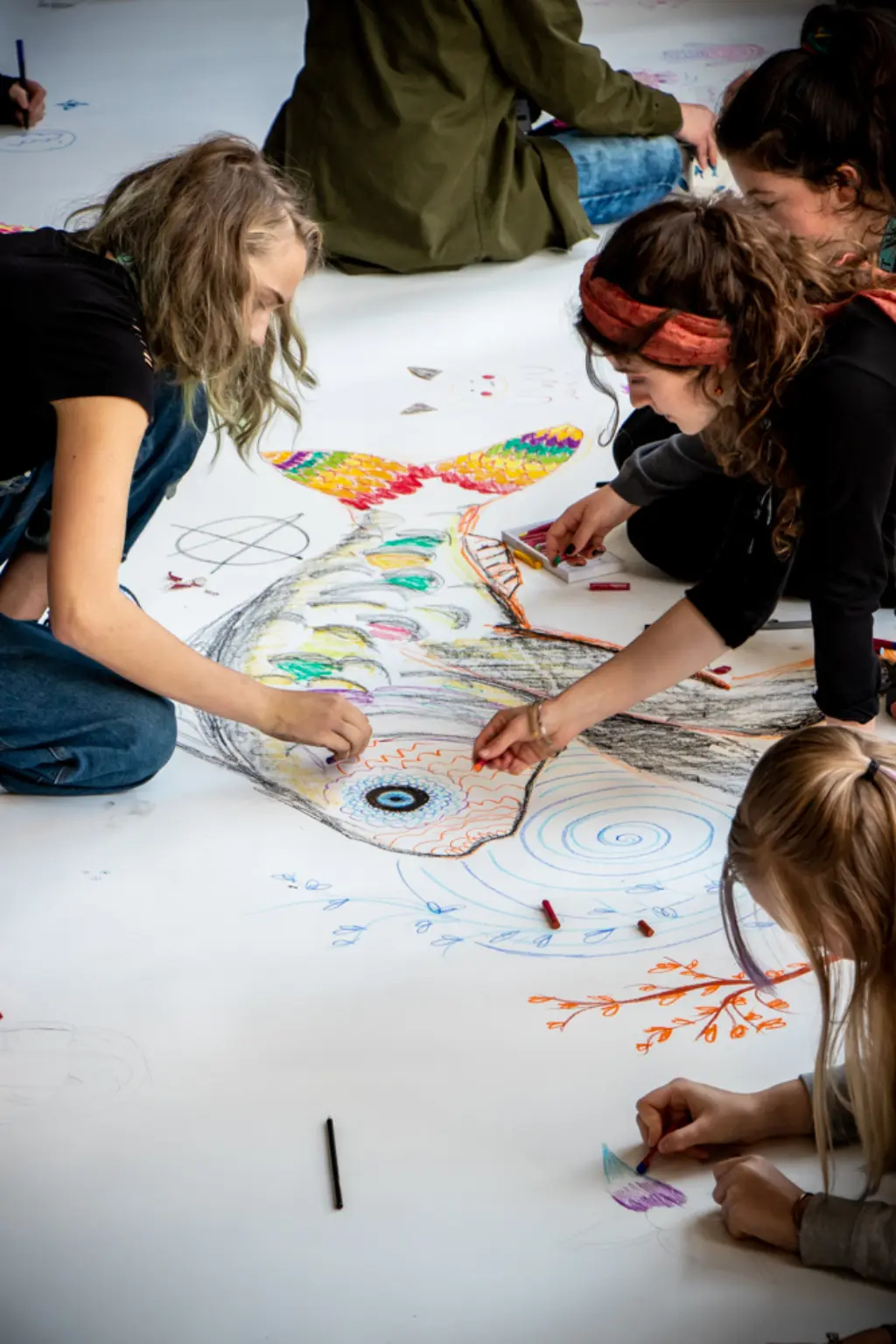 Young people collaborating to draw a big colourful fish.