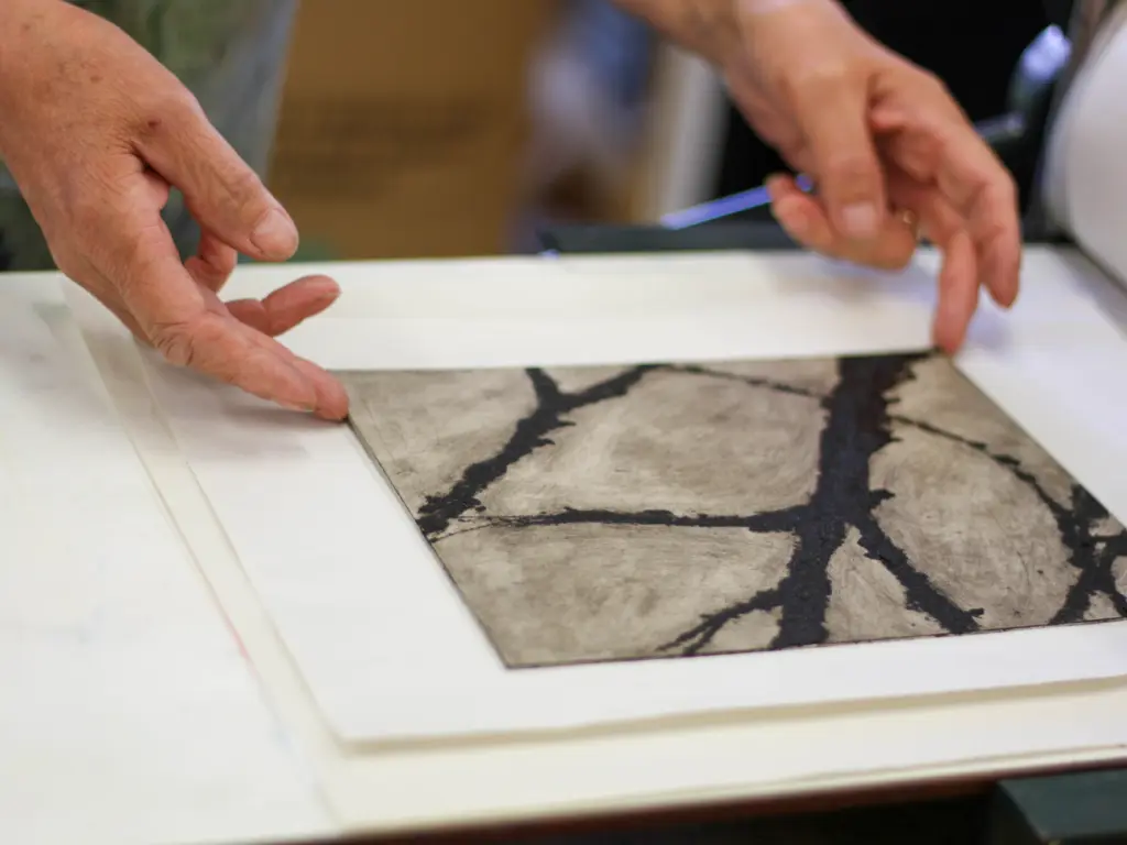 A close up shot of an intaglio style print coming out of the printing press.