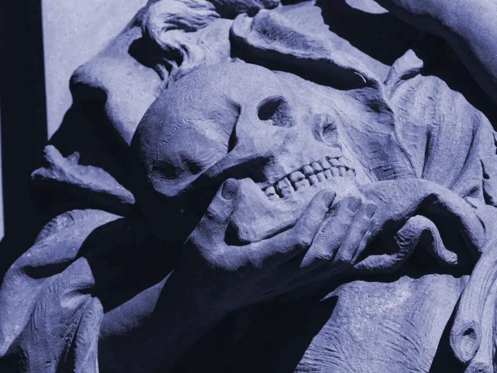 A tinted Black and White photo of a sculptural hand holding a skull.