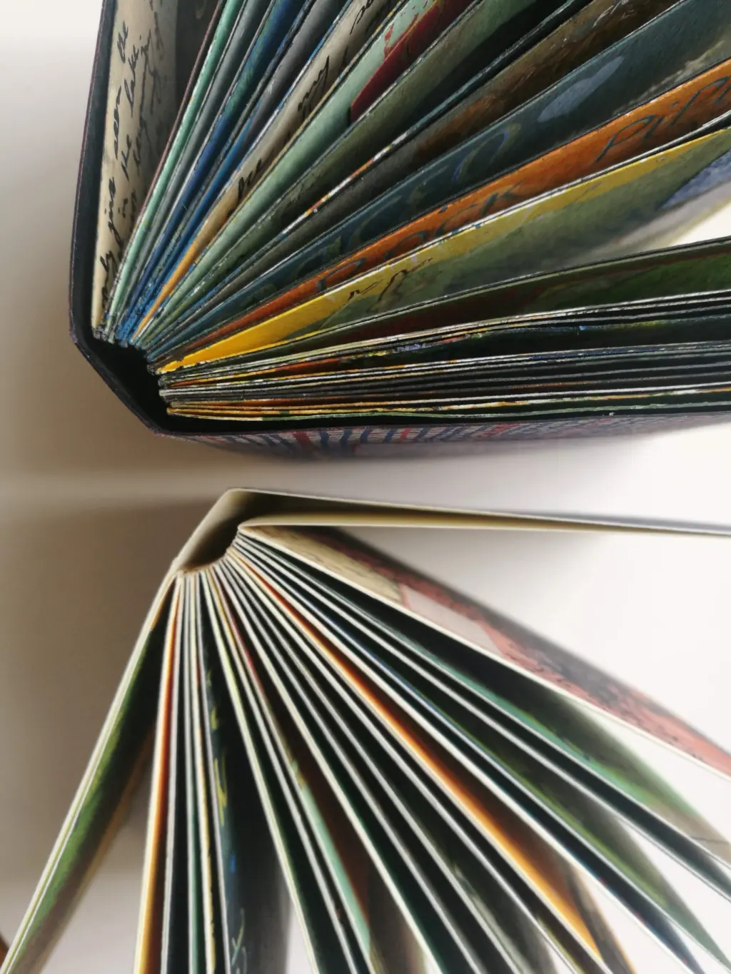 A birds-eye view of two books stood up on a table. You can see the multi-coloured pages fanned out.