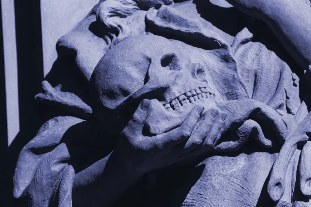 A tinted Black and White photo of a sculptural hand holding a skull.