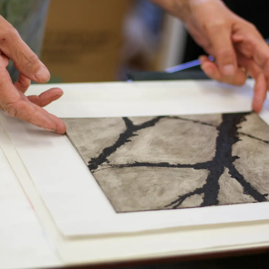A close up shot of an intaglio style print coming out of the printing press.