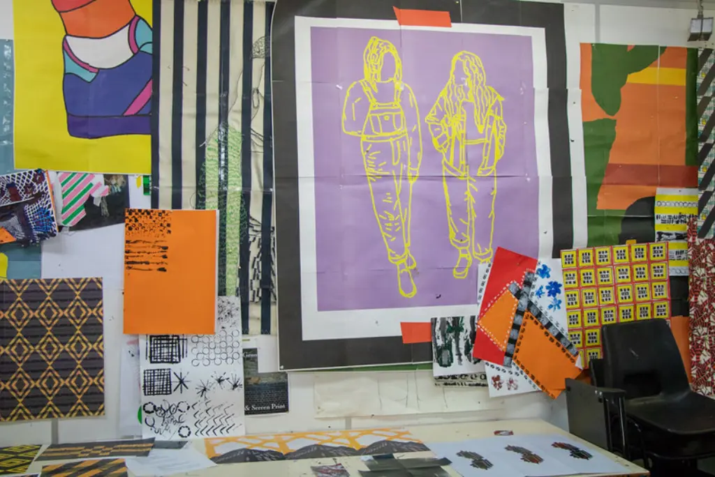 A wall with several pieces of fabric and colourful paper stuck to it, layered with fashion illustrations in funky colours.