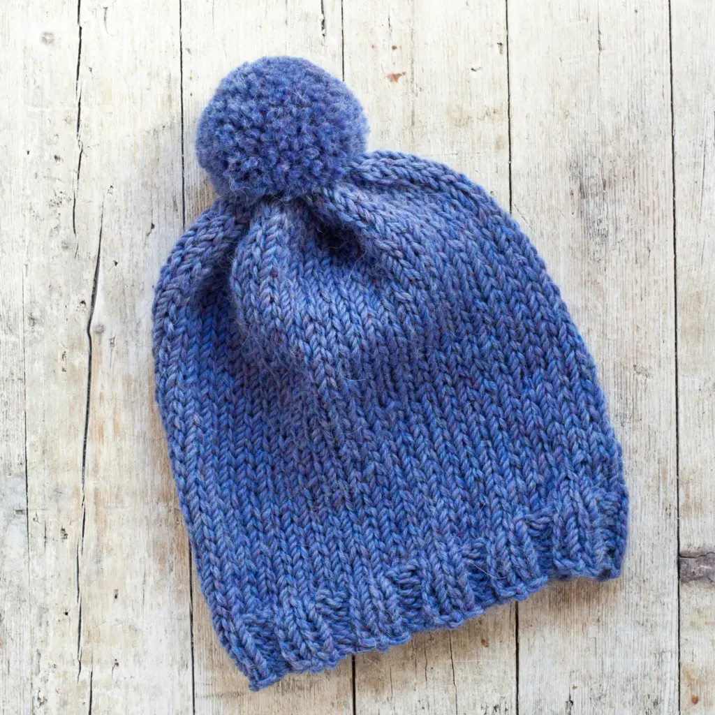 A cosy-looking blue beanie hat with a bobble on the end.